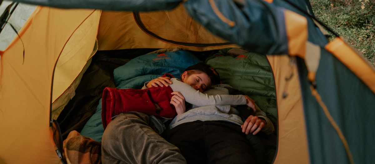 A cozy moment of a couple cuddling inside a tent, reflecting outdoor relaxation.
