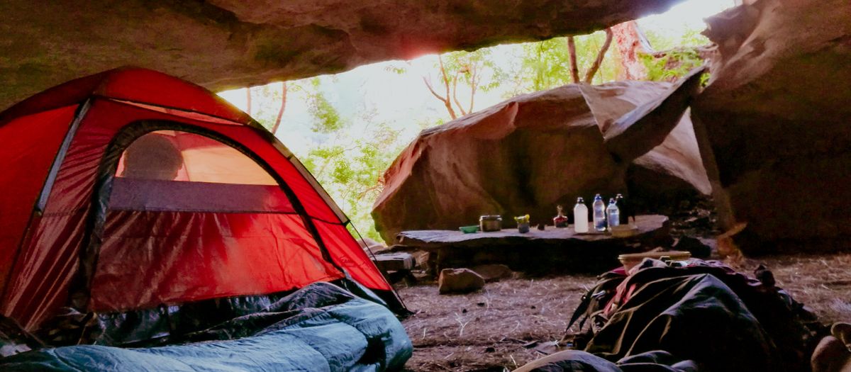 A sleeping bag laid open inside a tent at a campsite.