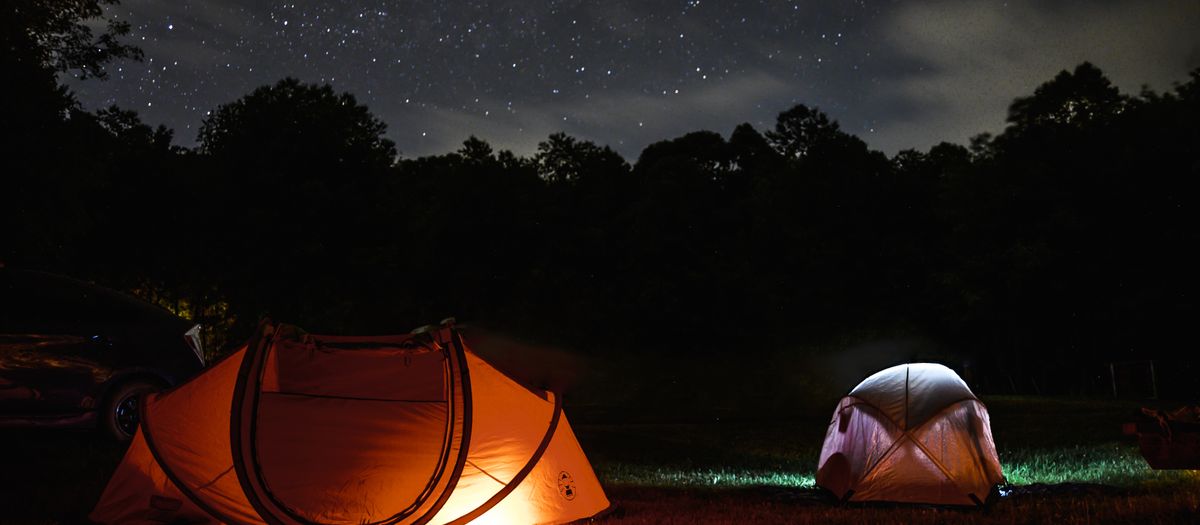 A lit backpacking tent at night on cold open ground.