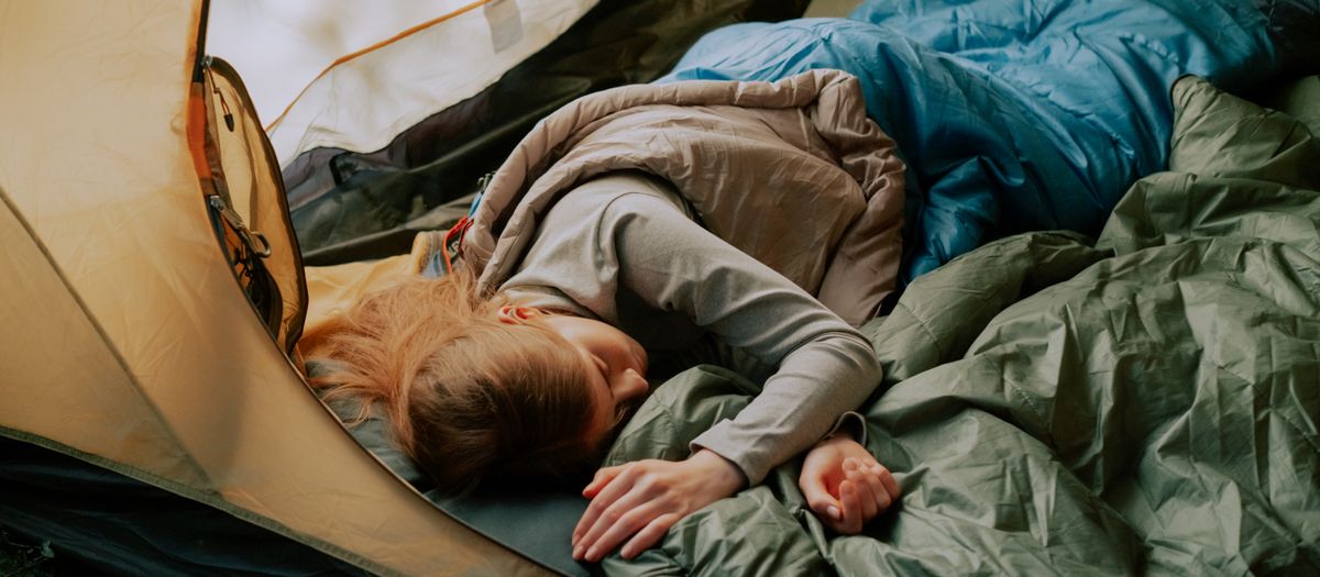 A cozy sleeping bag with a small pillow inside a tent.