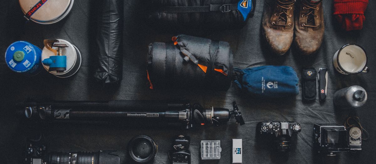 Flat lay of outdoor camping and photography equipment neatly organized.