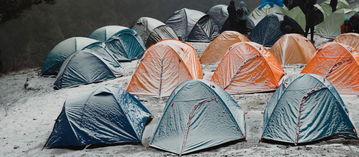 A vibrant campsite with colorful tents in a snowy forest in Singtur Range, India, capturing the essence of winter camping.