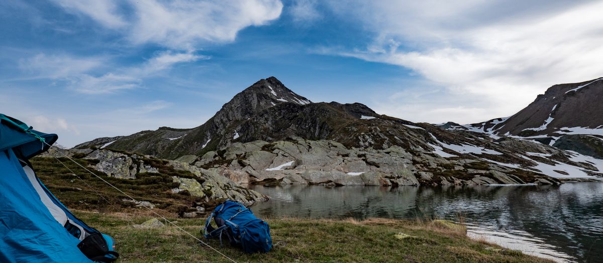 Scenic mountain landscape with tent setup by a tranquil lake, ideal for adventure seekers.
